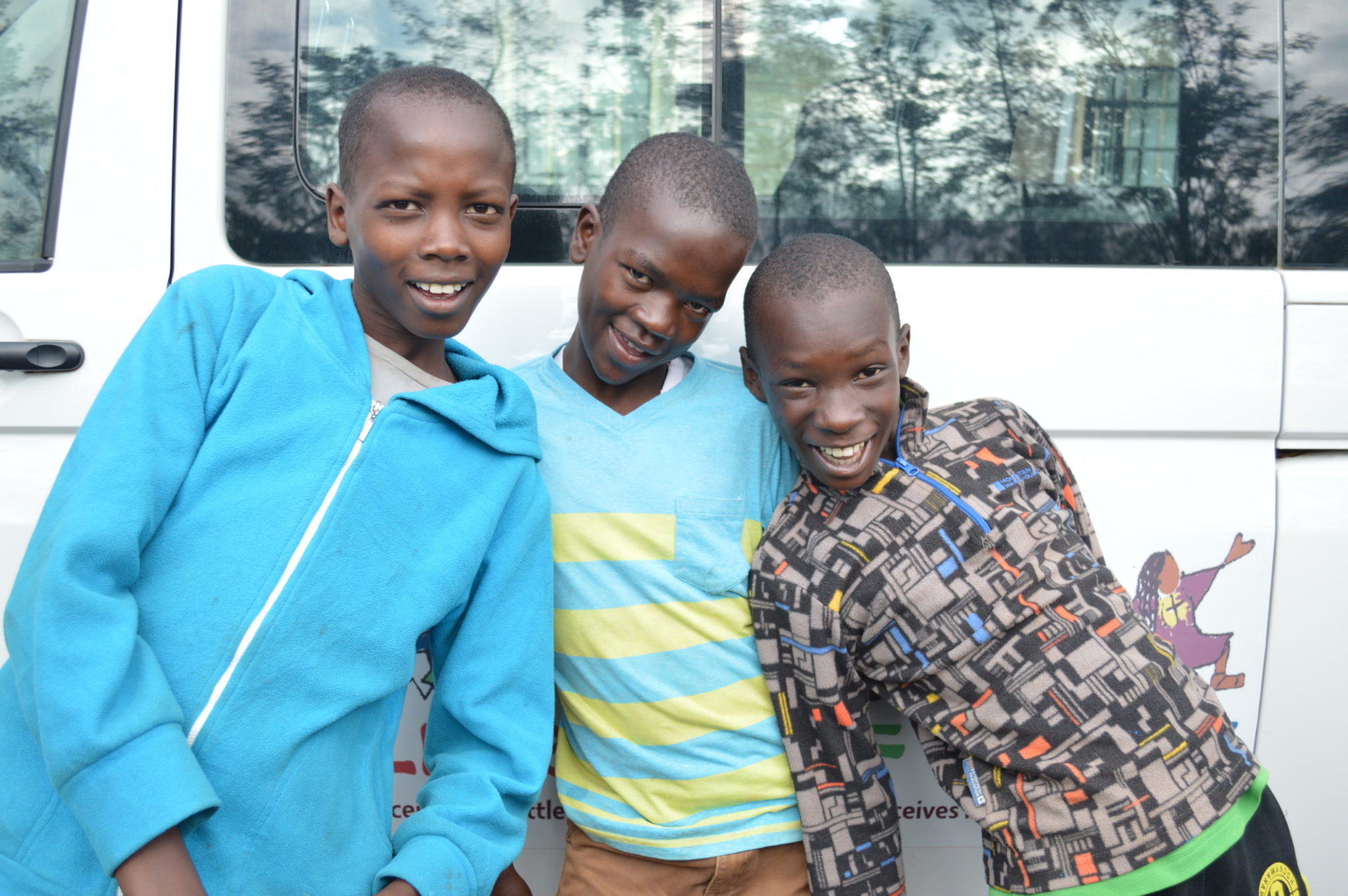 Children smiling in front of the COH van